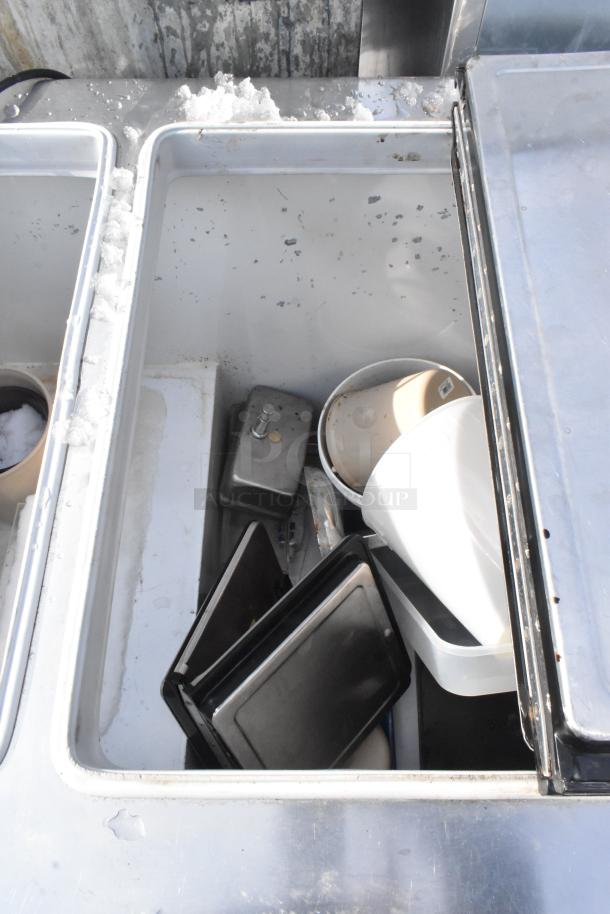 Kelvinator commercial chest freezer, stainless steel, with contents and ice buildup visible. Features commercial casters. 208-230V, 1 phase.