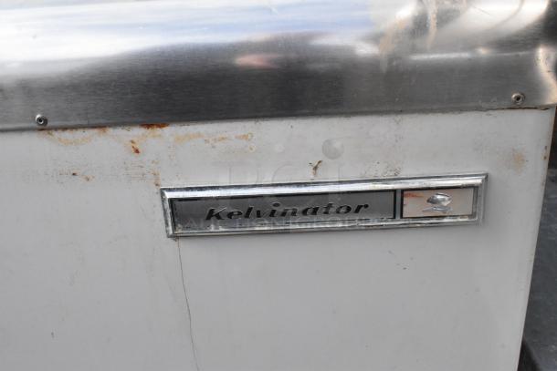 Kelvinator commercial chest freezer with visible rust and wear, stainless steel top, and brand name plate. Operates on 208-230V, 1 phase.
