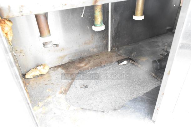 Commercial 3 bay sink interior with over-shelf; visible plumbing and signs of wear; three-door setup.