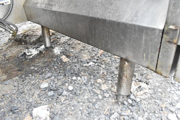 Commercial single bay sink with under shelf, stainless steel, visibly worn, situated outdoors on gravel surface.