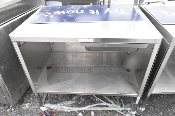 Commercial table with drawer, under shelf, on casters; stainless steel, moderate wear, suitable for industrial use.