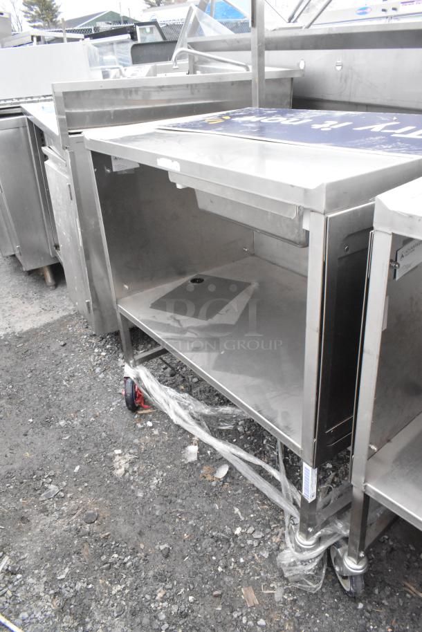 Stainless steel commercial table with drawer, under-shelf, and casters. Features sturdy construction and mobility for versatile use.