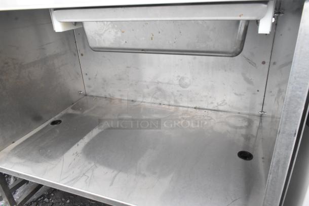 Commercial table with drawer, under shelf, and casters. Stainless steel, moderate wear, ideal for versatile storage.