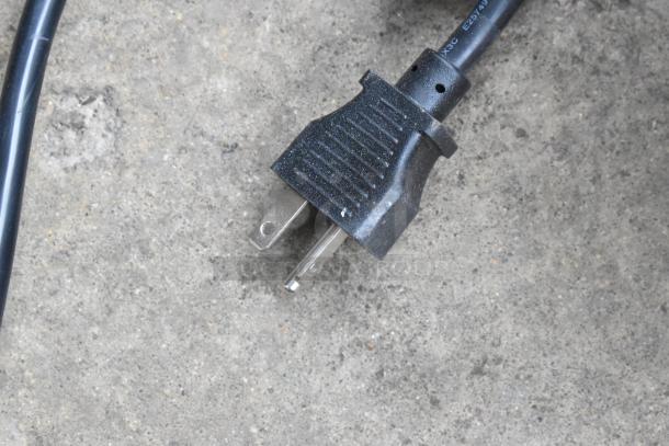 Close-up view of a power plug for the Avantco 177EG30N griddle, set on a concrete surface.
