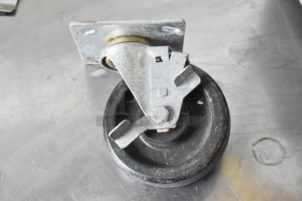 Lot of 4 commercial casters, metal brackets, black wheels, used condition. Visible wear, ideal for heavy-duty applications.