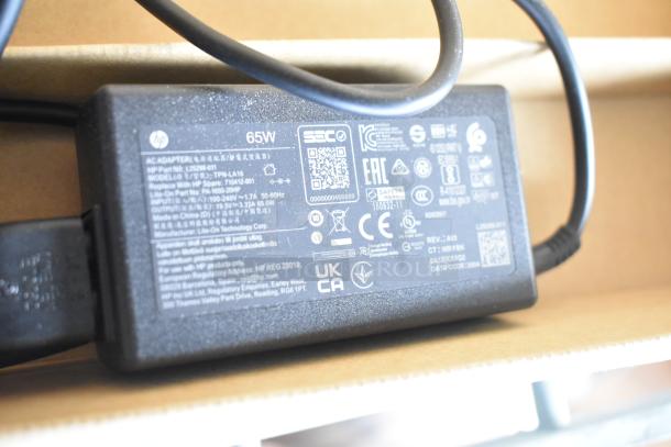 HP 65W power adapter with specifications and safety markings, model TPN-LA16, in good condition, included in auction lot.