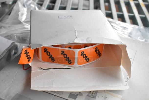 Box of orange 2026 stickers in packaging. Part of a lot including various items like Accucold Alarm and Robot Coupe blade.
