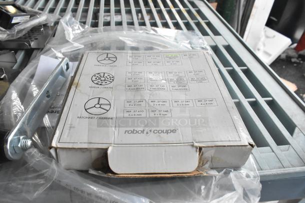 Robot Coupe food processor blade in original packaging, with visible reference numbers indicating slicer and grater types. Slight packaging wear.