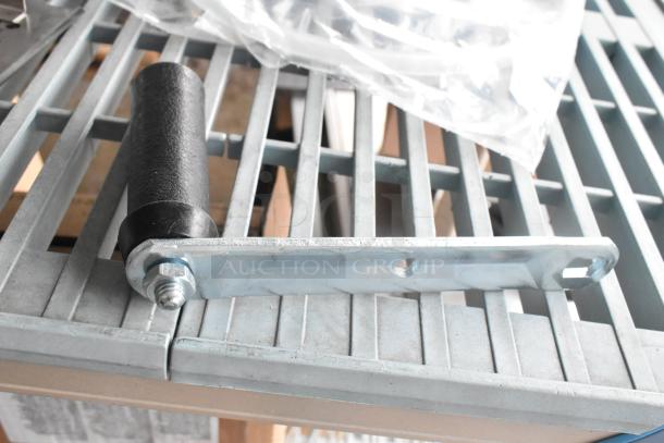 Industrial metal bracket with black cylindrical handle, part of 9-item auction lot, displayed on a metal grate.