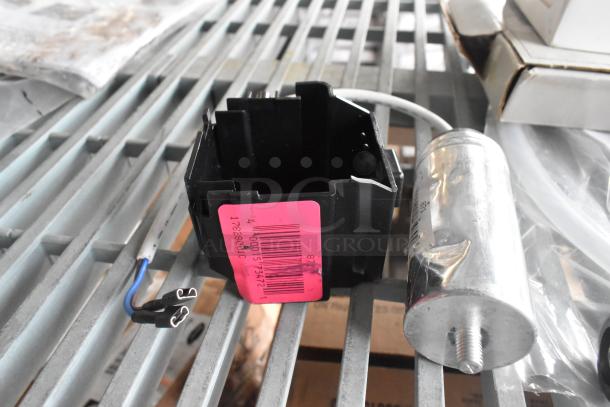 Nine items including a black framed part with a pink label marked 17828021RC, a metallic cylindrical component, wiring, and box packaging.