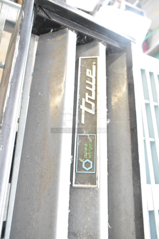 True cooler kickplate with label; part of lot including drop-in bin, wire basket, and food processor without lid.