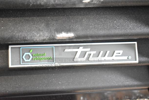2025 True TVM-48SL-HC reach-in cooler with "natural refrigerant" label, minor scratches visible.