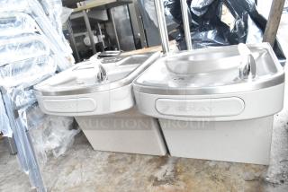 Pair of brand new Elkay wall mount water fountains, 115 volts, 1 phase. Scratch and dent condition, Elkay logo visible.