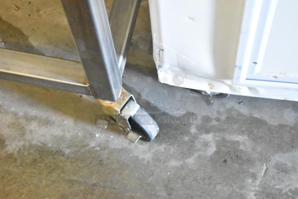 Belshaw Adamatic TG-50 stainless steel thermoglazing station on casters, showing partially visible commercial caster wheel.