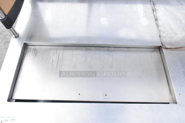 Commercial stainless steel counter with cut out, over shelf, and three doors. Good condition, suitable for kitchen or storage use.