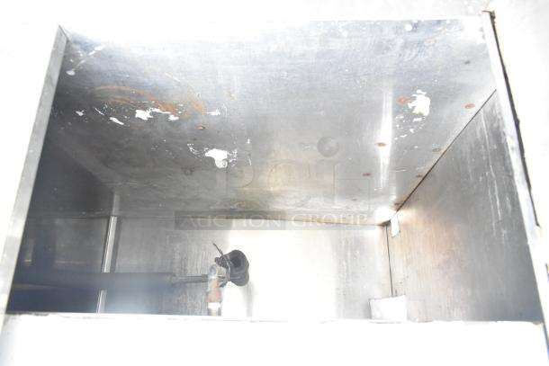 Commercial counter interior view showing metal surface with cut out, over shelf, three doors, and slight wear.