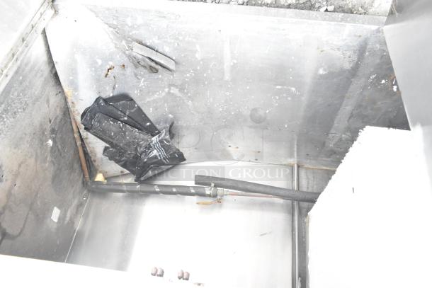 Commercial counter with cut out, over shelf, and three doors. Visible wear; interior shows piping and insulation.