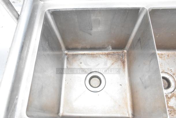 Commercial 3 bay sink with right side drain board, stainless steel, visible wear and stains, includes strainers.