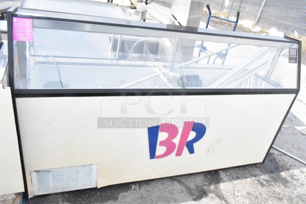 Commercial ice cream dipping cabinet with glass display and metal ice cream tub collars, includes branding and venting at base.