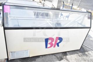 Commercial ice cream dipping cabinet with glass display and metal ice cream tub collars, includes branding and venting at base.