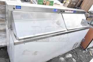 Commercial ice cream dipping cabinet with sliding glass lid, stainless steel frame, and visible exterior wear marks.