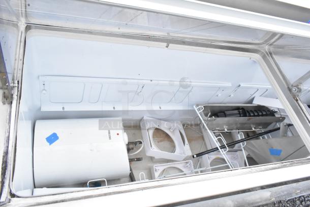 Commercial ice cream dipping cabinet with glass top, stainless steel interior, visible components, in used condition.