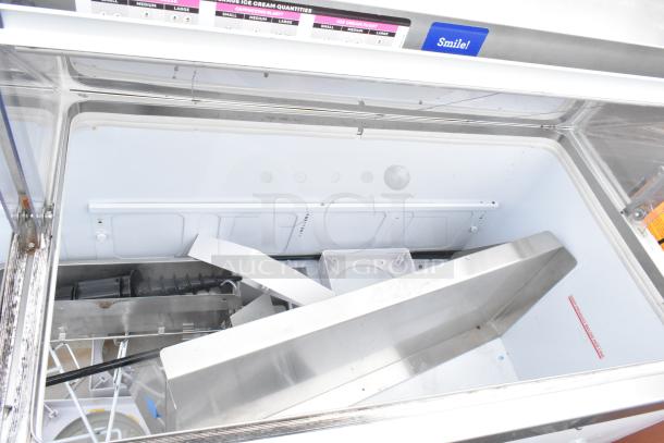 Commercial ice cream dipping cabinet with interior view. Features include stainless steel components and cooling elements. Includes signage for sizes and flavors. Good condition.