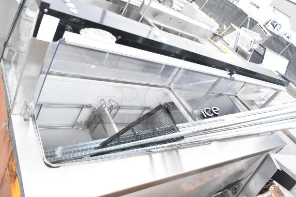 Commercial ice cream dipping cabinet, stainless steel, glass top, used condition with interior racks and markings visible.