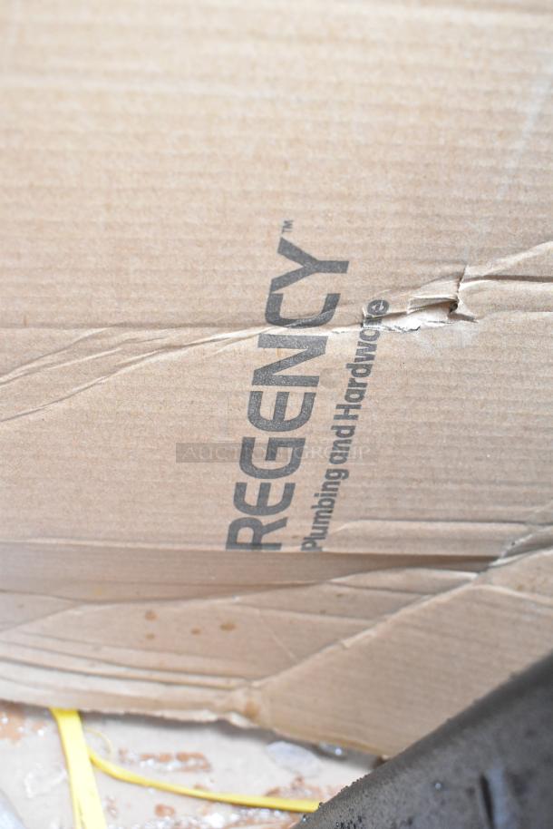 Cardboard box with "Regency Plumbing and Hardware" label, showing wear and tear. Contains catering items, including Cambro case.