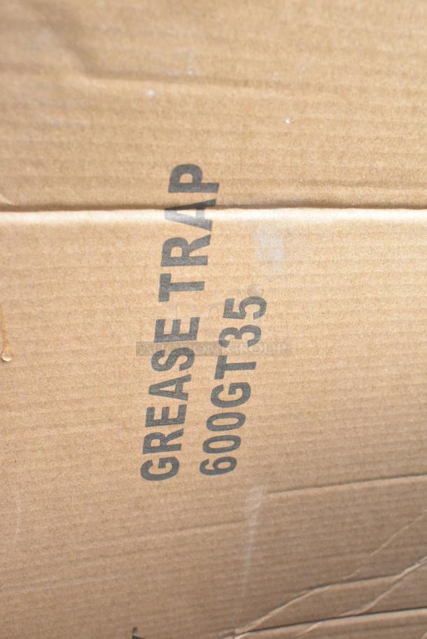 Cardboard box labeled "GREASE TRAP 600GT35," part of a "Scratch and Dent" auction lot with catering equipment.