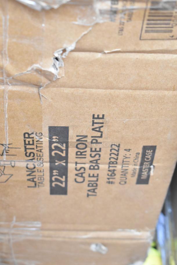 Damaged cardboard box containing Lancaster 22"x22" cast iron table base plates. Box shows visible tears. Items are brand new.