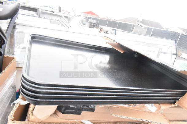 Stack of new black trays, part of 10-piece scratch and dent auction lot. Includes bussing carts. Unopened packaging.