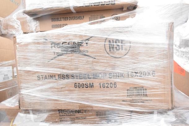 Boxes of new scratch and dent items including Regency stainless steel mop sinks and double tier overshelf, wrapped in plastic.