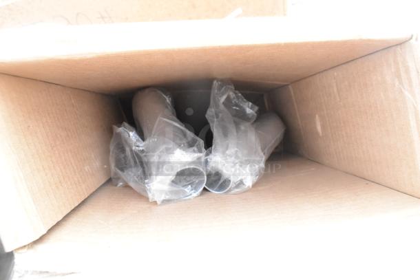 Cardboard box with plastic-wrapped items inside; part of a scratch and dent auction lot including table and platform truck.