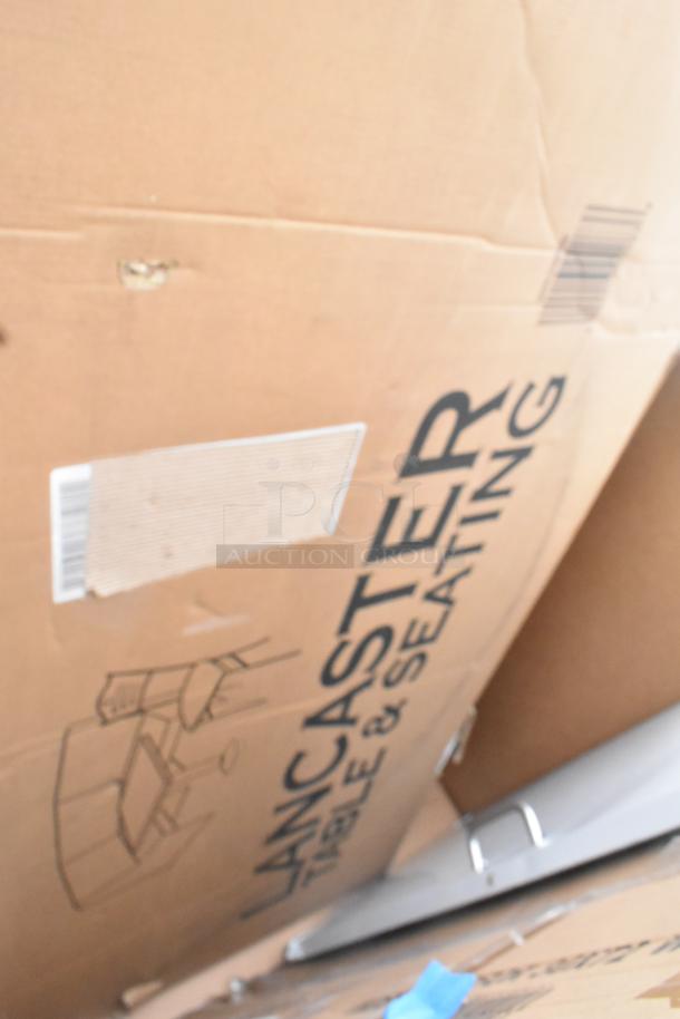Cardboard box labeled "Lancaster Table & Seating," containing brand new scratch and dent items, including a table and platform truck.