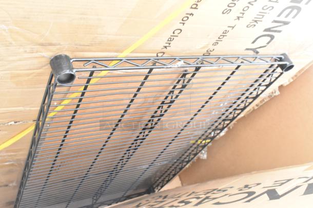 Black metal grid platform leaning against cardboard packaging of new scratch and dent items, including tables and trucks.