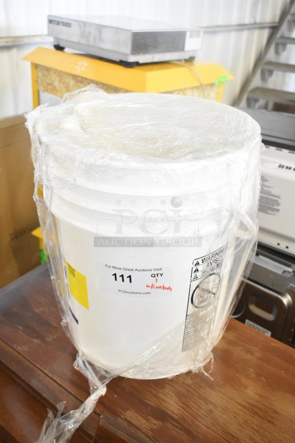 White poly bucket wrapped in plastic, contains knives. Label reads "111 QTY 1" and "PCIauctions.com."