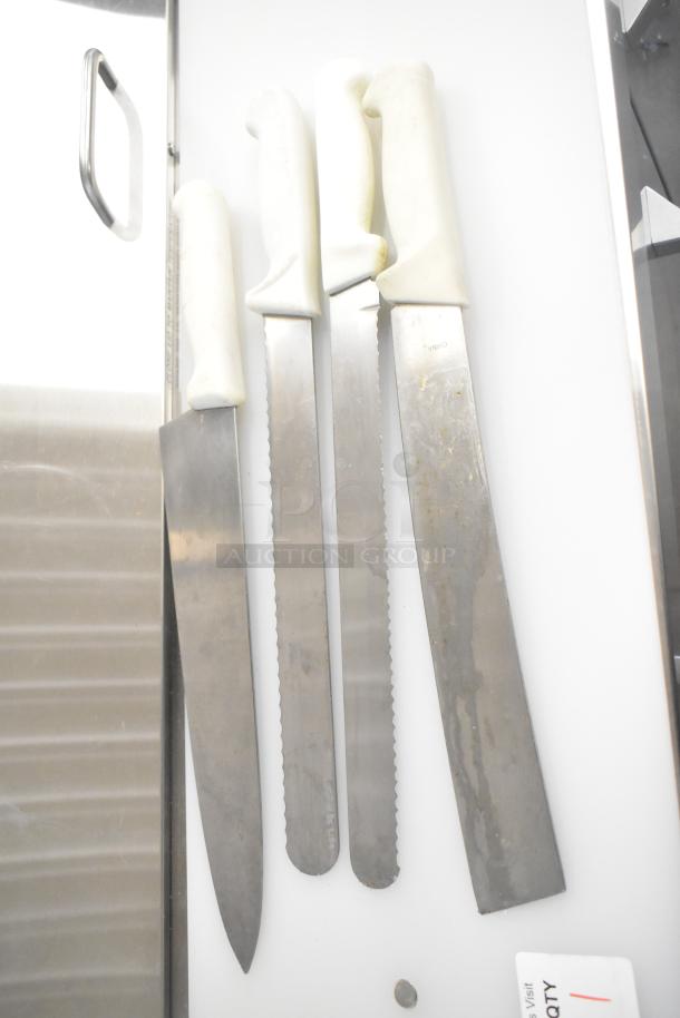 Set of knives with white handles, showing wear, laid on a white surface. Marked "China" on blades. No bucket visible.
