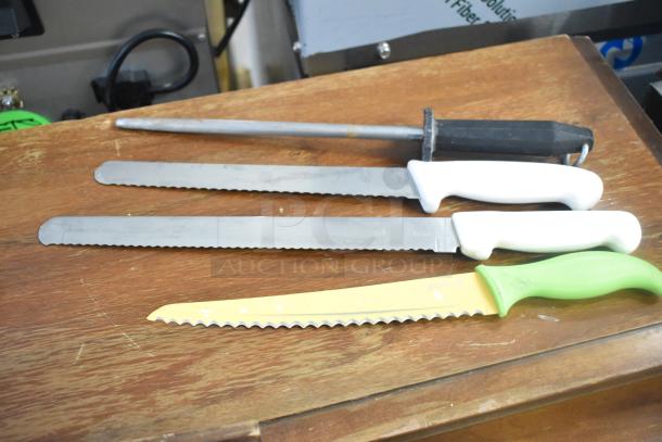 Set of three serrated knives and sharpening rod on a wooden surface, featuring white and green handles.