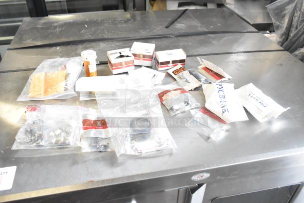 Assorted items including light bulbs and packaged components on a table. Items in mixed condition with various labels.