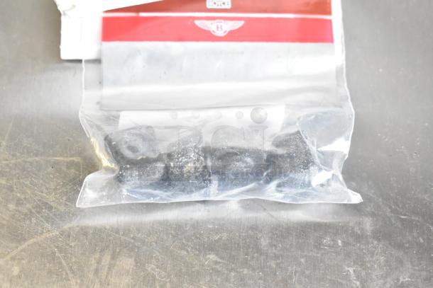 A bag of small metal components inside a plastic package. Background includes a red and white label.
