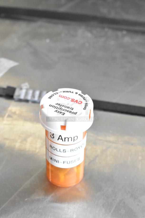 Rolls-Royce 3 Amp mini-fuses in CVS prescription bottle on metallic surface.