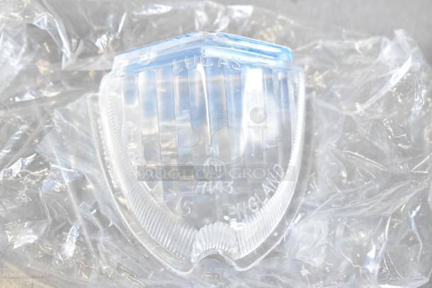 Clear Lucas light cover with markings, including "Lucas," "England," and "E11 7143," wrapped in protective plastic.