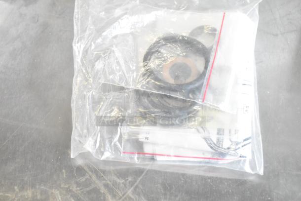 Plastic bag containing various items, including rings and documents, labeled "ALL ONE MONEY! Lot" with light bulbs.