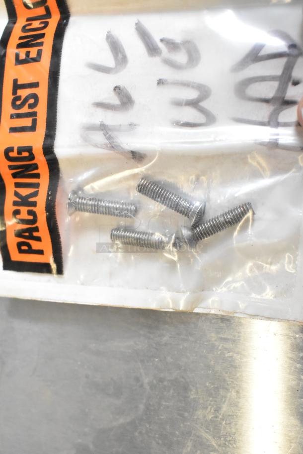 Clear plastic bag with metal screws, labeled "Packing List Enclosed." Black marker writing visible.