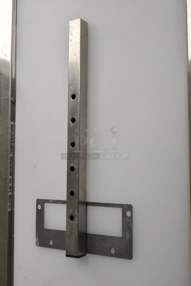 Metal bracket with a rectangular base, featuring multiple screw holes, in new condition. Label reads "CLOSE LID TO MAINTAIN TEMPERATURE."