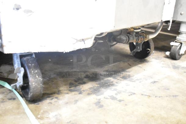 Toastmaster TCT-1627 R commercial tandoor oven base view, showing wheels and gas connection. Needs cleaning, natural gas-powered.