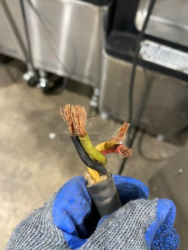 Close-up of frayed wiring on a stainless steel Taylor C70733 soft serve machine. Power cable issues visible.