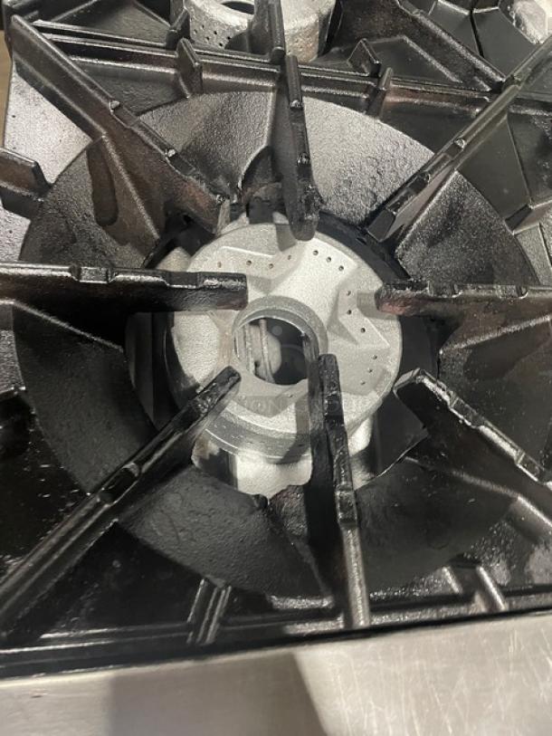 Radiance gas-powered 6-burner range from Turbo Air with stainless steel finish, includes backsplash and overhead salamander shelf. Oven rack and adjustable legs visible.