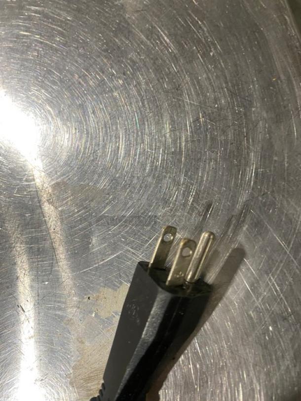 Close-up of an electrical plug on a textured metallic surface, likely part of the Vollrath Slushy Machine model CBE117.